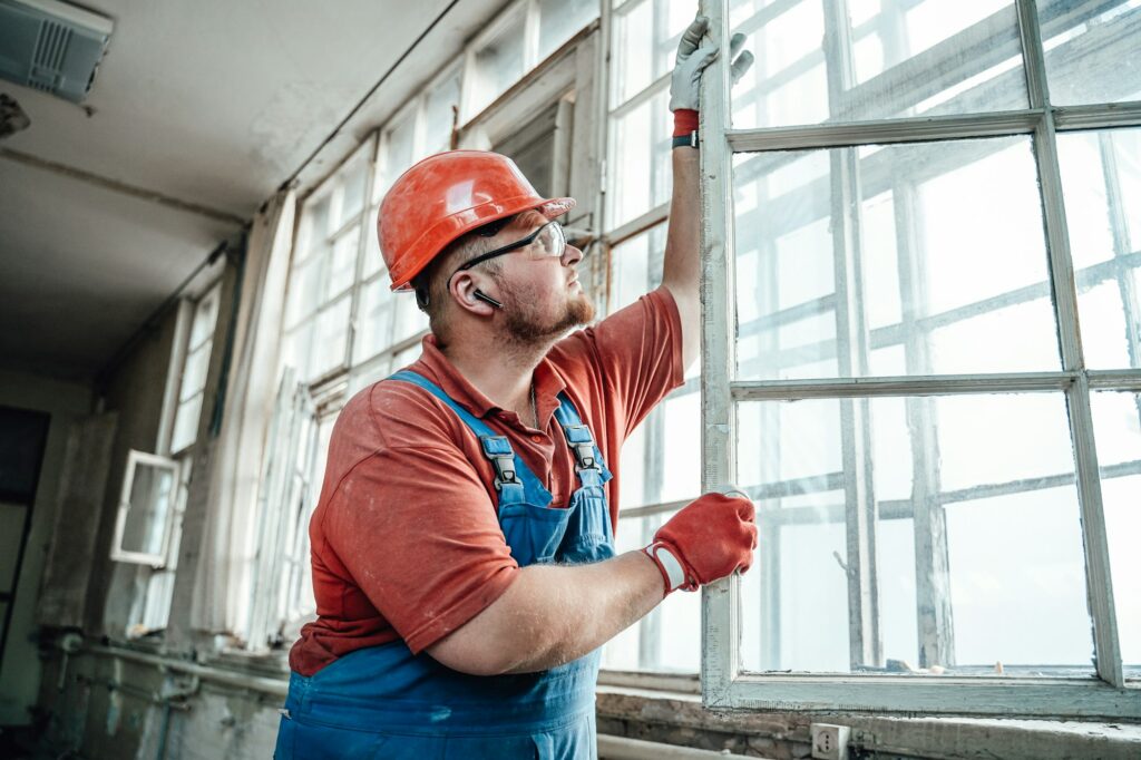 Concentrated builder working with a glass window at a construction site