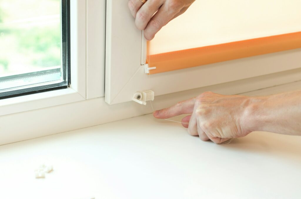 Installation of roller blinds. Male hands close-up install blinds on the window.