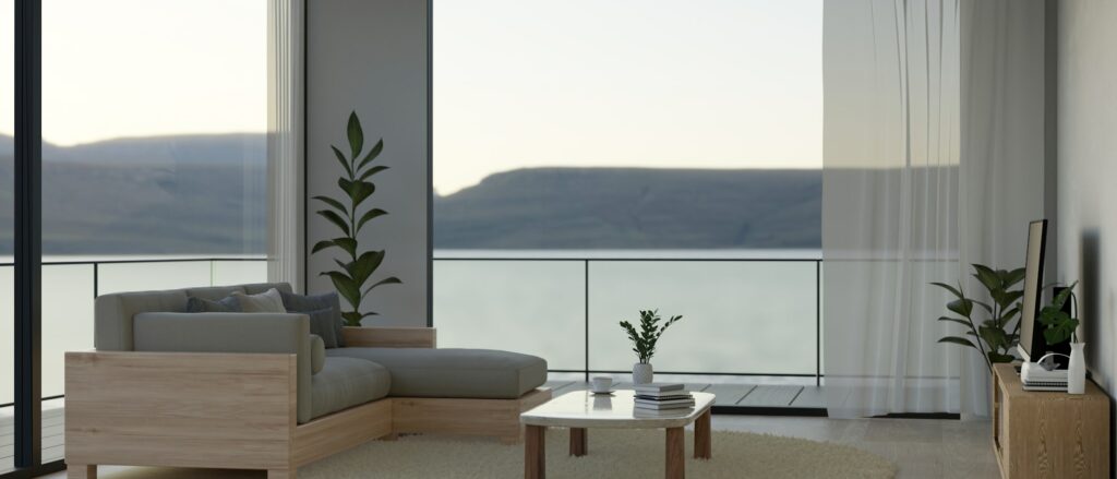 Modern living room with couch, coffee table, smart TV, large glass window with nature view, balcony